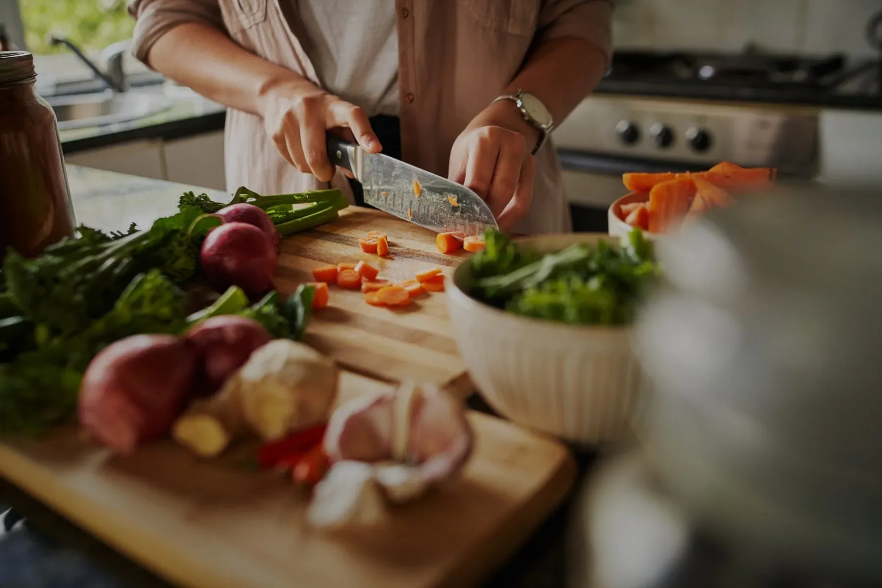 Person chopping fresh vegetables on a wooden cutting board